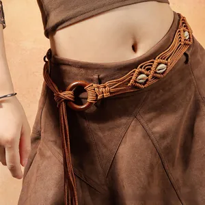 Gros plan sur une ceinture tressée bohème avec boucle ronde en bois et détails coquillage