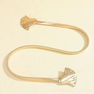 Detailed close-up of golden ginkgo leaf buckle on an elastic metal snake chain belt