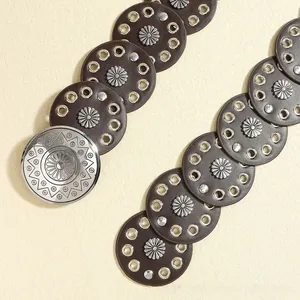 Close-up of bohemian brown belt with silver floral rivets and vintage sunburst buckle