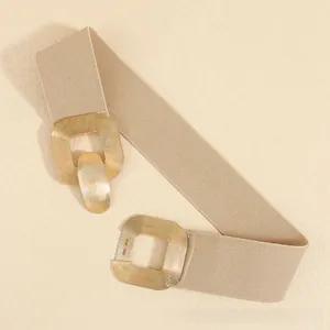 Macro detail of the beige elastic belt featuring a vintage gold double-loop buckle design