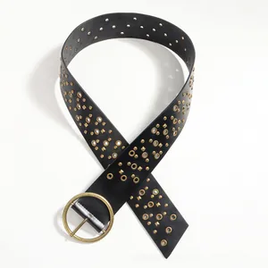 Detail of black punk leather belt with vintage gold eyelets and large round buckle