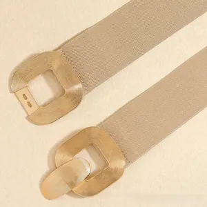 Close-up of beige elastic waist belt featuring a textured golden square metal buckle