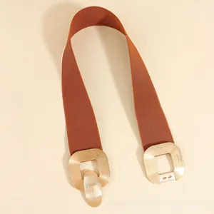 Detail showing wide tan elastic waist belt with gold square buckle on beige background