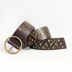 Detail view of dark brown punk belt with large gold round buckle and metallic rivets