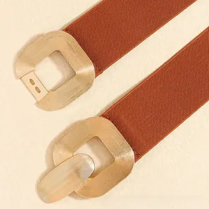 Detailed macro view of the gold square metal buckle with striped texture on an elastic belt