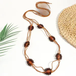 Détail d'une ceinture tressée marron avec des perles en bois et une pierre en résine ambre