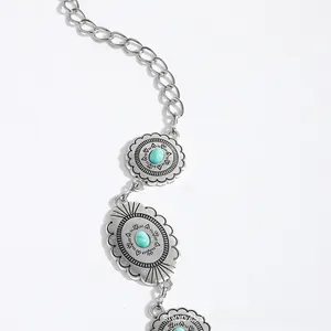 Macro view of bohemian metal waist chain with turquoise inlays and tribal engravings
