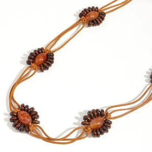 Détail d'une ceinture tressée vintage avec perles ethniques et cordons marron