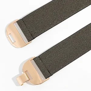 Détail de la ceinture élastique tissée noire et dorée avec boucle en métal doré poli