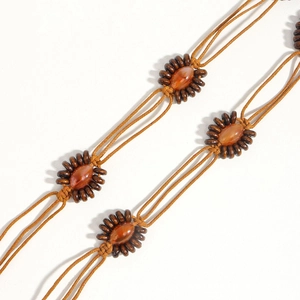 Détail d'une ceinture tressée bohème vintage avec perles d'ambre et tubes en bois foncé
