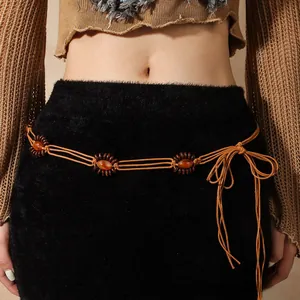 Détail de ceinture tressée vintage marron avec perles oranges nouée sur une jupe