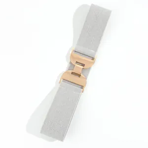 Détail d'une ceinture élastique argentée avec boucle double arche en métal or rose