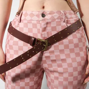 Detail of brown PU leather belt with double-row gold rivets and horseshoe buckle