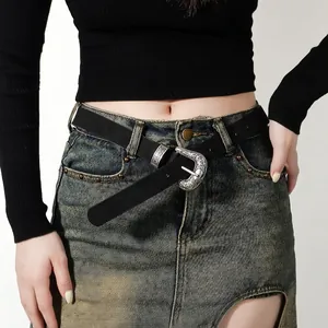 Women's black leather belt with ornate silver floral buckle on vintage denim skirt