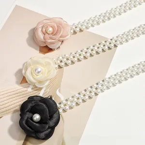 Detail view of triple camellia flower pearl belts in pink, cream, and black styles
