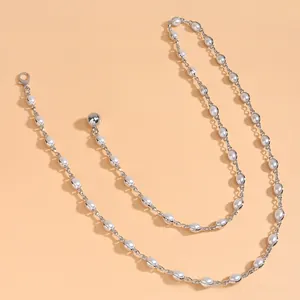 Détail de la ceinture chaîne perlée argentée élégante avec fermoir sur fond orange