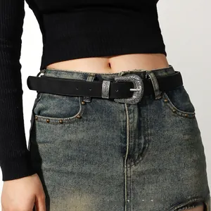 Detail view of black vintage leather belt with ornate silver engraved buckle on blue denim