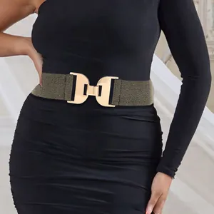 Détail de la large ceinture élastique avec boucle en métal doré sur une robe noire