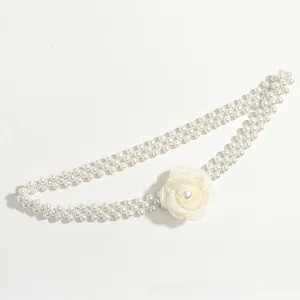 Detail view of double-strand pearl belt with an elegant cream camellia flower ornament