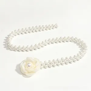 Macro detail of camellia fabric flower and double-row pearl waist chain with elegant finish