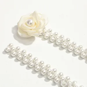 Detailed close-up of a white pearl woven belt featuring a satin camellia flower detail