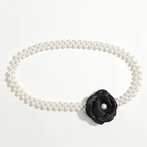 Detail of elegant double-row pearl waist chain with large black fabric camellia flower