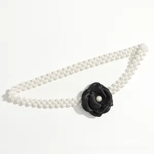 Detail of elegant double-row pearl belt featuring a classic black camellia flower ornament