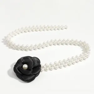 Detail of elegant double-row pearl waist chain with a black silk camellia flower charm