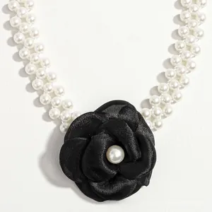 Detail of double-layer pearl belt featuring a large black fabric camellia flower charm