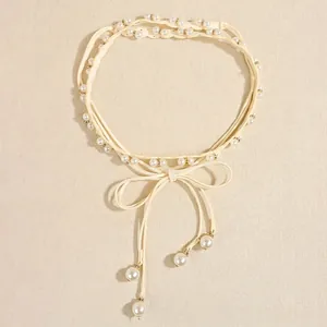 Elegant woven pearl belt with gold accents and bow tie detail on a beige background