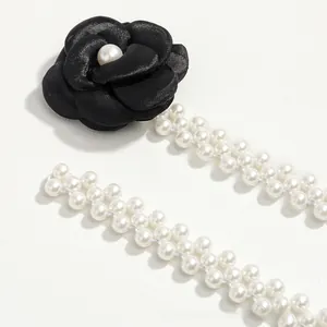 Detail of camellia flower belt with faux pearls and black fabric for dresses