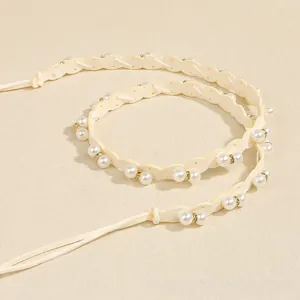 Close-up of pearl woven belt featuring wavy white ribbon and gold diamond accents