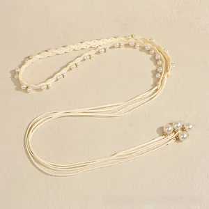 Detail of elegant cream-white woven waist chain with faux pearls and sparkling rhinestones