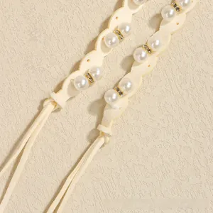 Macro shot of elegant beige faux leather waist chain with white beads and gold metal spacers