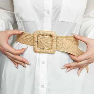 Detail of minimalist straw woven belt with a square buckle on a white shirt
