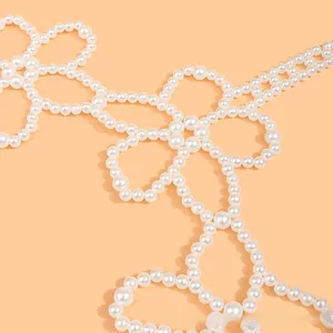 Detailed close-up of intricate white pearl body chain with handcrafted floral patterns