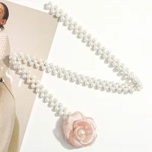 Close-up of white double-row pearl belt with a pink satin camellia flower decoration