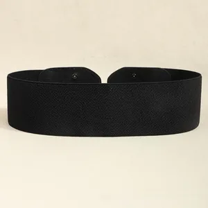 Détail d'une large ceinture élastique noire avec texture cuir et boutons-pression en métal