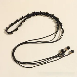 Detailed macro view of black pearl woven waist chain with golden rhinestone separators