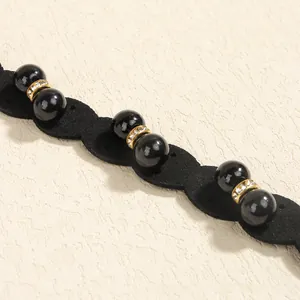 Close-up of black velvet belt with pearls and gold crystal rings for elegant dresses