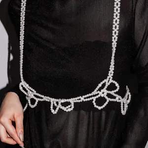 Detail view of elegant white pearl body chain with floral beaded pattern on black mesh top