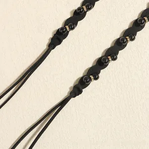 Detailed close-up of a black woven waist chain featuring pearls and gold rhinestone beads