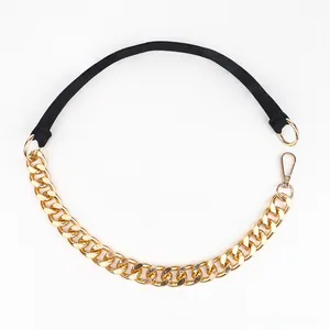Close-up of golden chunky metal chain linked with black elastic waist belt band