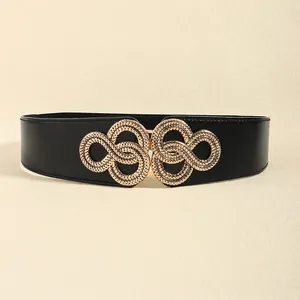 Détail de la large ceinture élastique noire avec boucle infinie dorée sur fond beige