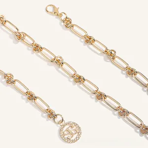 Détail de la ceinture chaîne dorée avec fermoir mousqueton et pendentif évidé