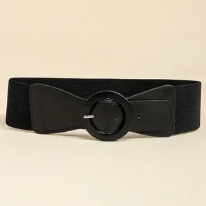 Detail of a wide black elastic waist belt featuring a large round PU leather buckle