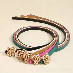 Detail view of five assorted slim leather belts featuring elegant metallic rose buckles