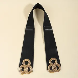 Détail d'une ceinture large élastique noire pour femme avec boucle dorée en forme de huit