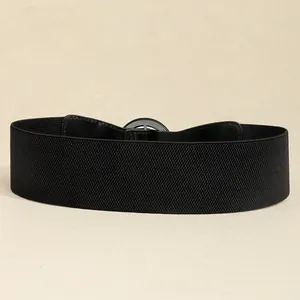 Close-up of black elastic wide waist belt featuring a polished silver circular metal buckle