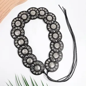 Detail of bohemian black leather belt with silver engraved metal discs and lace-up tassel
